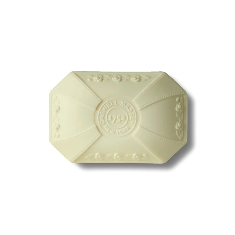 An ivory-colored, octagonal triple-milled soap bar embossed with decorative floral patterns and the words "well made 1792 New York Botanical Garden" at the center, presented on a plain Caswell Massey Peony Luxury Bar Soap 100gm.