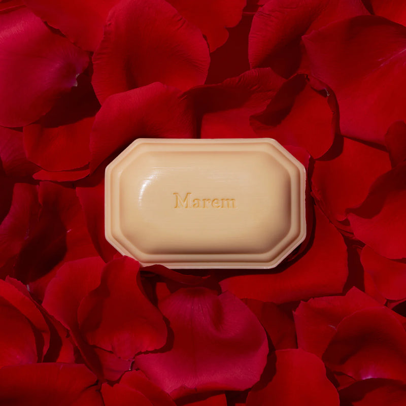A bar of triple-milled soap from the Caswell Massey Marem Three-Soap Set placed in the center of a backdrop composed of vibrant red rose petals.
