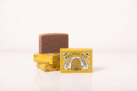 A bar of Primitive House Farm Wild Honey Soap beside two yellow boxes with labels featuring a bee and honeycomb designs, staged against a clean, white background.