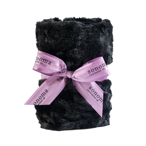 A Sonoma Lavender Onyx Mink Heat Wrap neatly folded and tied with two light purple ribbons printed with "sonoma lavender co." on a white background, incorporating aromatherapy for muscle relief.