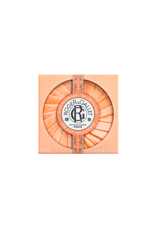 A circular Roger & Gallet Carnation soap bar in an orange-coral hue, featuring intricate embossed designs and a floral fragrance, with the brand logo centered within a regal frame, against a matching background.