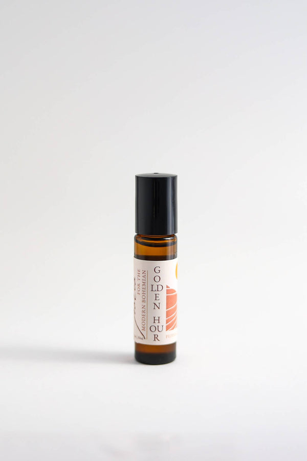 A small Nustad Family Ranch Essential Oil Perfume Roller bottle labeled "golden hour," filled with organic jojoba oil, featuring a white and orange design, placed upright against a plain white background.