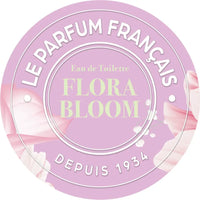 An elegant perfume label for "Le Parfum Français Flora Bloom Eau de Toilette", featuring soft pink tones and a timeless charm floral arrangement. The text "le parfum français depuis 1934" enc