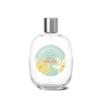 A clear perfume bottle with a silver cap and a label featuring the text "Le Parfum Français Isla Paradis Eau de Toilette," symbolizing an island paradise.