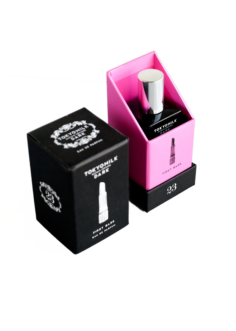 Two Margot Elena TokyoMilk Dark First Base No. 23 Eau De Parfum boxes, one black and one pink, displayed side by side with a Cedarwood-scented perfume bottle atop the pink box.