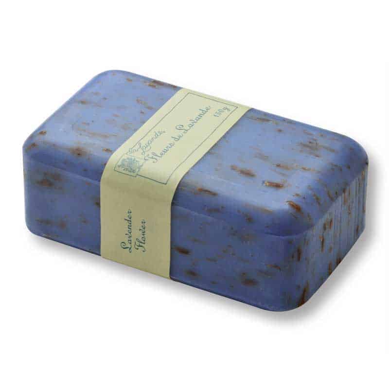 A bar of La Lavande Joie de Vivre Lavender Flowers Soap with flecks of French lavender flowers within, wrapped with a beige label that reads "lavender - handmade in Quebec". The soap has a smooth texture and a rectangular shape.