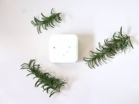 A minimalist composition featuring a square white plate with four small bites arranged in a circle, surrounded by sprigs of Homegrown {77833} Co - Stop and Smell the Rosemary on a white background.
