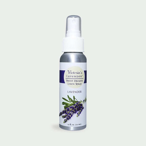 A silver spray bottle labeled "Victoria's Lavender - Sweet Dreams Lavender Linen Spray" with an image of lavender flowers on a white background, formulated with lavender essential oil.