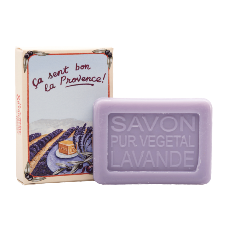 A bar of La Savonnerie de Nyons Provence Lavande 25gm soap labeled "savon pur végétal lavande" next to its packaging box with an illustration depicting Provence and the text “ça sent bon la Provence!”