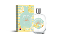 A clear perfume bottle labeled "Le Parfum Français Isla Paradis Eau de Toilette" next to its matching teal and gold packaging box adorned with floral designs, both featuring French text.