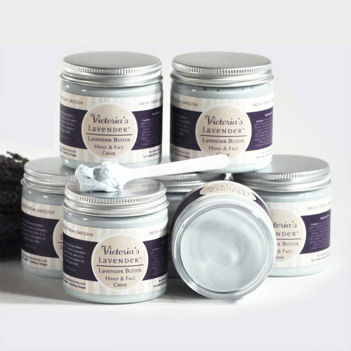 Several jars of Victoria's Lavender - Lavender Butter Face & Hands - 4oz displayed with one jar open, showcasing the cream, against a white background with a lavender bundle.