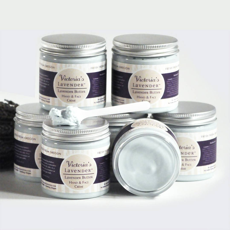 Several jars of Victoria's Lavender - Lavender Butter Face & Hands 8oz moisturizing cream, displayed with an open jar in front and dried lavender in the background. Labels show the product is made in Oregon.