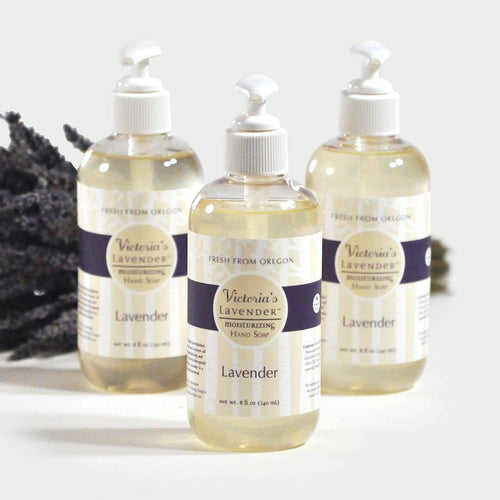 Three bottles of Victoria's Lavender Liquid Hand Wash - Lavender 8oz with pump dispensers, displayed against a white background with a dark lavender sprig to the left.