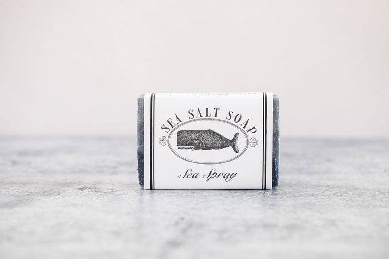 A bar of Primitive House Farm - Forty Fathoms Sea Spray Soap in minimalistic packaging with a whale illustration. The soap is placed on a simple, light grey surface.