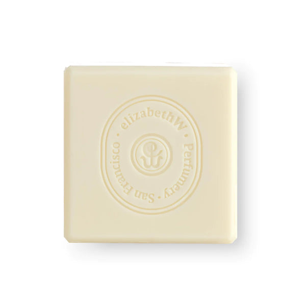 A square, pale yellow triple-milled bar of elizabeth W Atelier Violette Soap with a raised logo and decorative text embossed on its top surface, isolated on a white background.