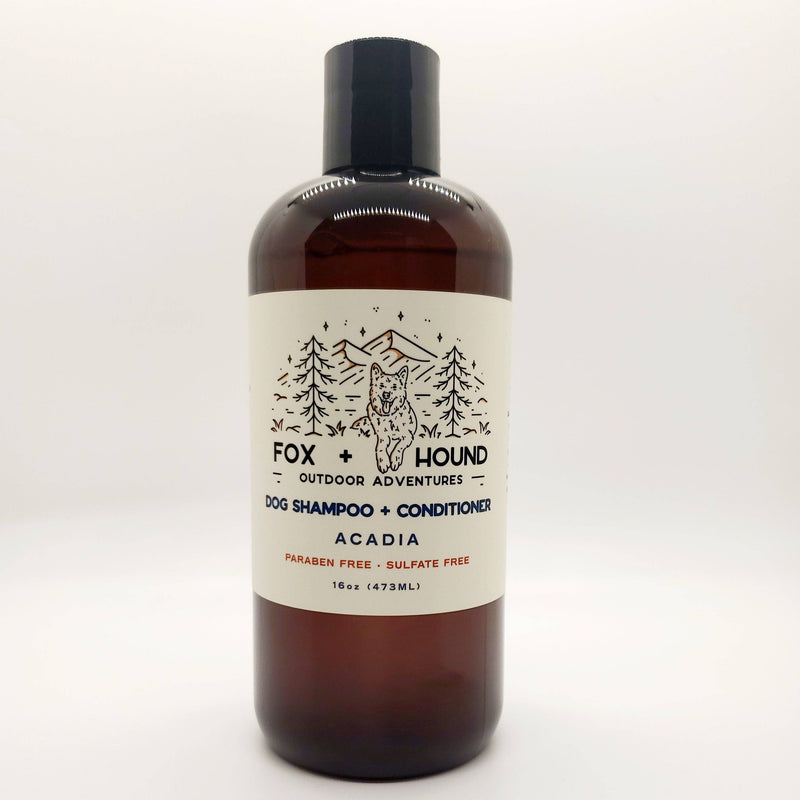 A brown bottle of "Fox + Hound Acadia Dog Shampoo + Conditioner - National Park Series" featuring a forest and mountain label design. The text indicates it's paraben-free shampoo and sulfate-free.