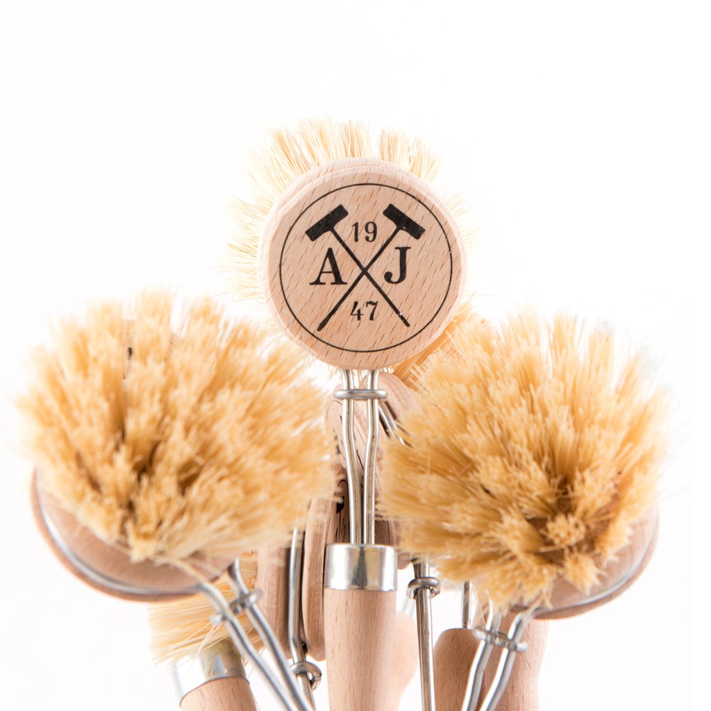 A group of Andrée Jardin Tradition Handled Dish Brushes with natural bristles, made in France, standing upright, with one featuring a logo "aj 19 47" burned into the wood on a circular disc.