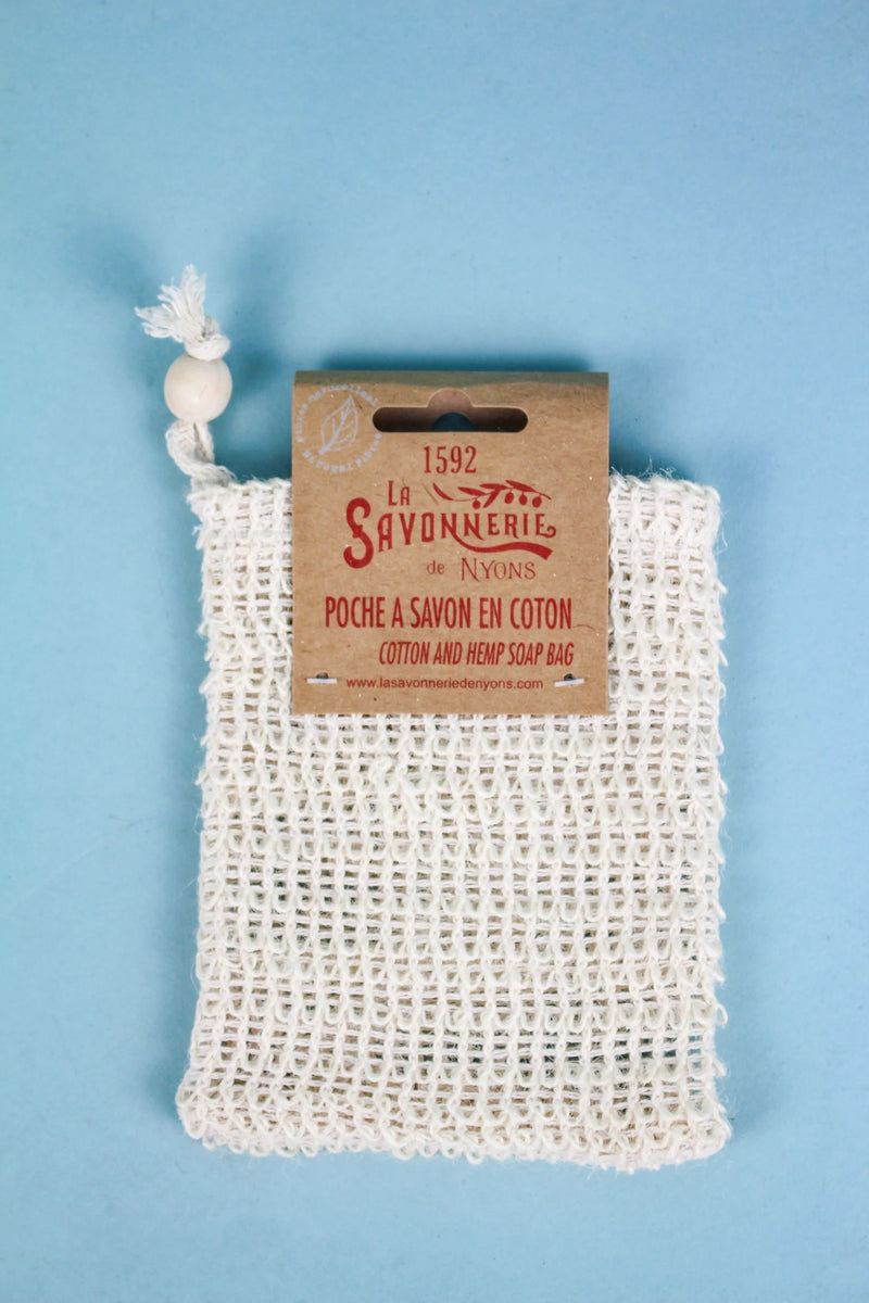 A La Savonnerie de Nyons cotton soap pocket with a cardboard label detailing the brand "la savonnerie de nyons" against a light blue background. Made in France.