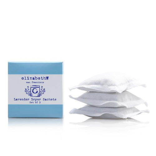 A set of three white French lavender dryer sachets next to their blue packaging labeled "elizabeth W Lavender Dryer Sachets Set of 3.