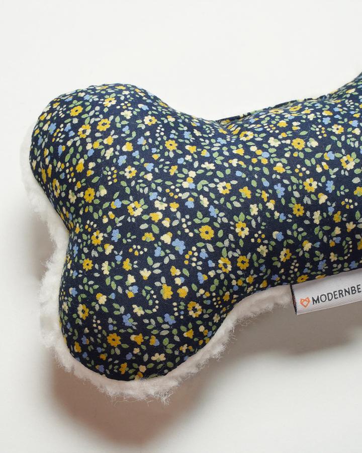 A close-up of a MODERNBEAST Lavender Zenbone - Midnight Floral dog toy with an organic lavender floral pattern in shades of blue and yellow on a white background. The tag shows the brand "ModernBeast.