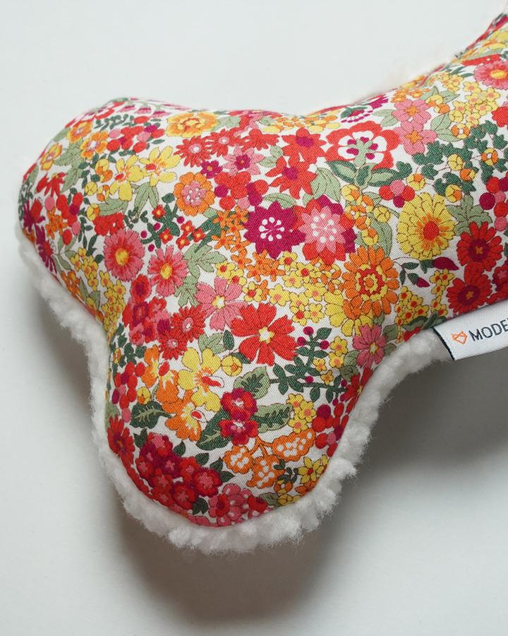 A MODERNBEAST Lavender Zenbone - Red Floral neck pillow with a white fleece edge, infused with organic lavender, resting against a plain white background.