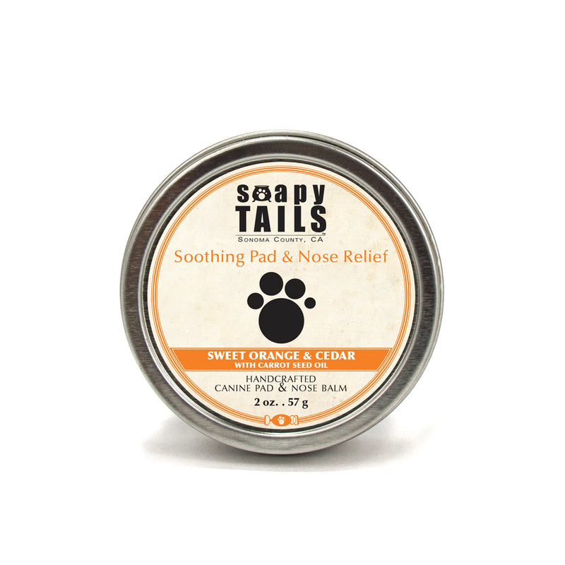 A circular tin of Three Sisters Apothecary Soapy Tails Dog Pad & Nose Balm 2 oz with a label featuring the product name, "sweet orange & cedar," and details about its purpose as a pad and nose relief.