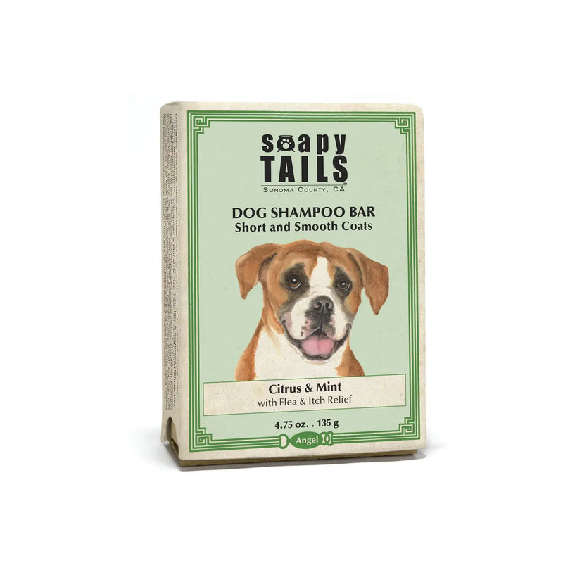 A Three Sisters Aphothecary dog shampoo bar packaging labeled "Soapy Tails Citrus & Mint" featuring an image of a cheerful brown and white dog. The product is for short and smooth coats, with citrus and mint scents, weighing
