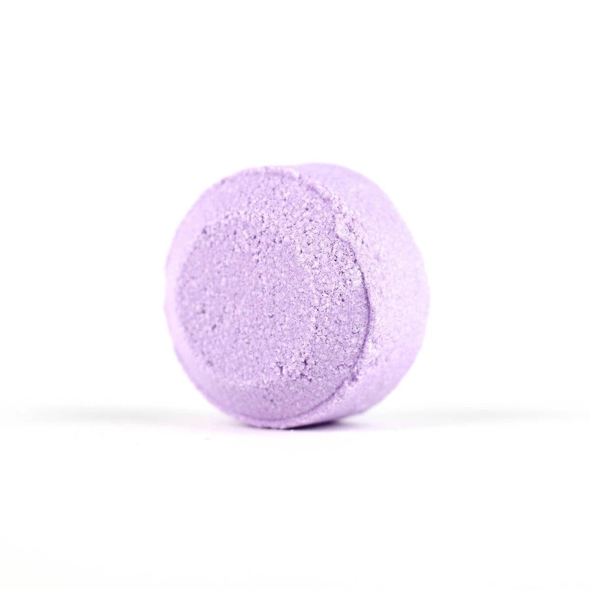 A single Spinster Sisters Lavender Shower Steamer isolated against a white background. Infused with lavender essential oil, the shower steamer has a slightly textured surface, indicating its fizzy quality.