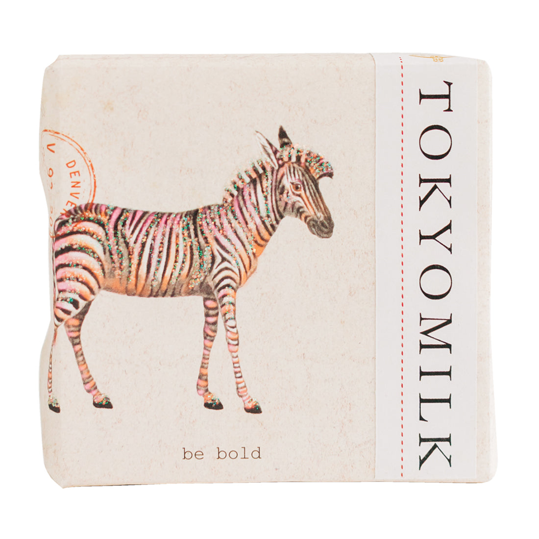 A notebook with an illustrated zebra featuring colorful stripes on a beige background. The words "be bold" and "Margot Elena TokyoMilk Finest Perfumed Soap - Be Bold (Zebra)" are printed on it.