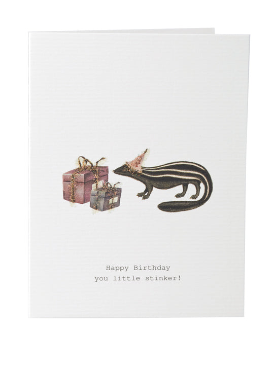A TokyoMilk Greeting Card featuring an illustration of a skunk next to two hand-glittered gift boxes, with the text "happy birthday you little stinker!" printed at the bottom, by Margot Elena.