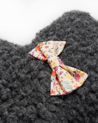 A colorful floral bow tie on a textured grey woolen fabric featuring a MODERNBEAST Lavender Bedtime Bear - Grey Plush w Wildflower Bowtie scent.