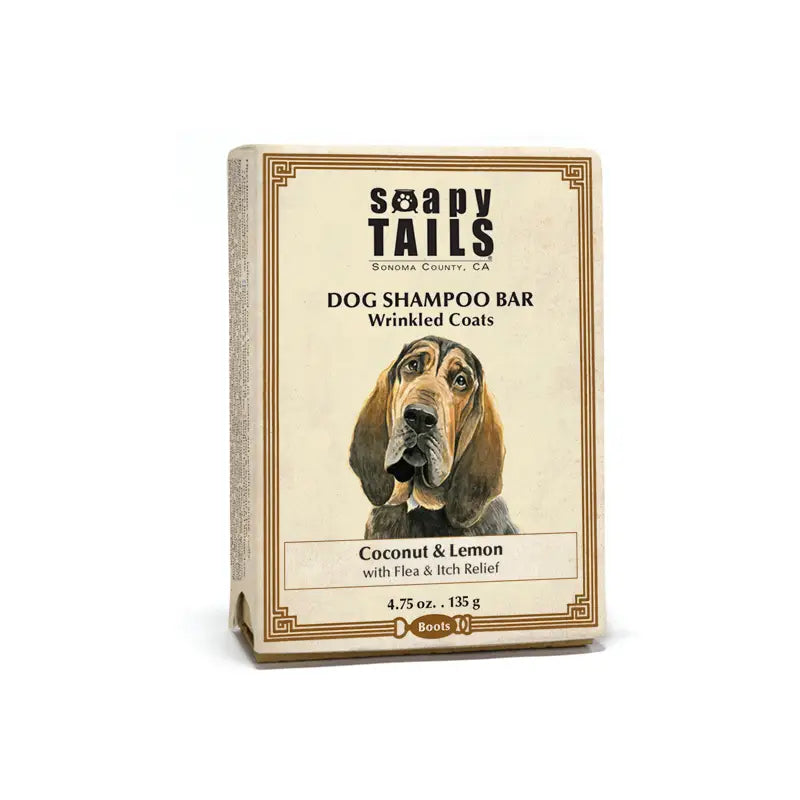 A dog shampoo bar labeled "Soapy Tails Coconut & Lemon Dog Shampoo Bar for Wrinkled Coats" with an illustration of a wrinkled dog on the packaging. It features coconut & lemon scent and flea relief, noted as being from Sonoma County, from Three Sisters Aphothecary.