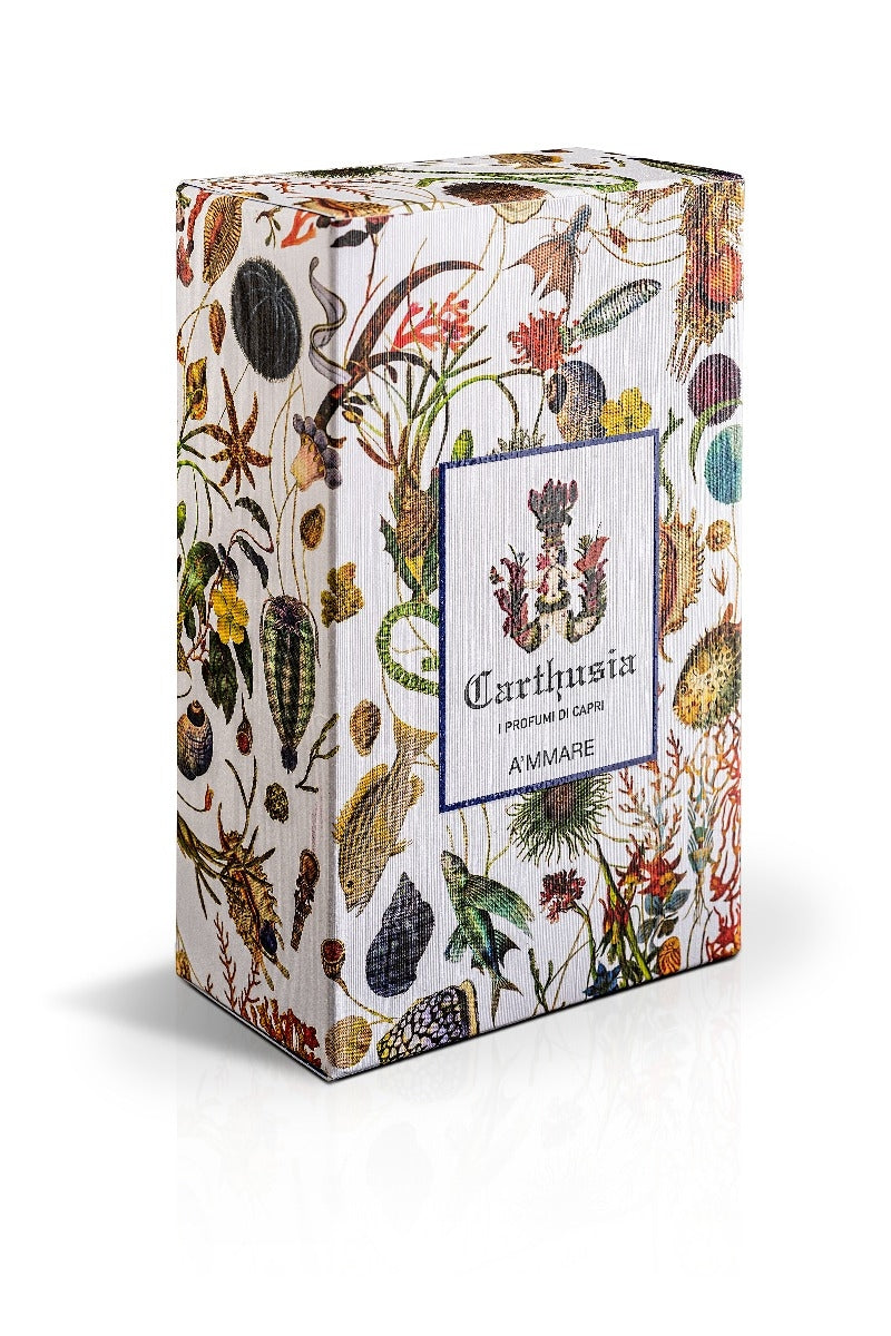 A square box featuring a detailed, colorful Capri garden and insect print, including a label with text "Carthusia A'mmare Eau de Parfumo 100ml" on a white background by Carthusia I Profumi di Capri.