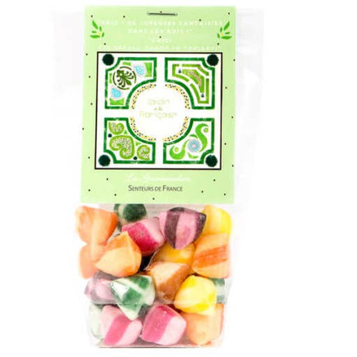 Transparent plastic packaging filled with colorful, pyramid-shaped candies, displayed below a green and white label with decorative motifs and text for Senteurs De France Nantes Berlingot Candies.