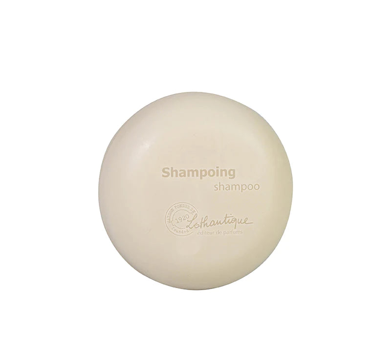 A Lothantique 75g Solid Shampoo Donkey Milk with the embossed text "shampooing shampoo" and "lush boutique - éthique et partenaires" on a plain, light background.