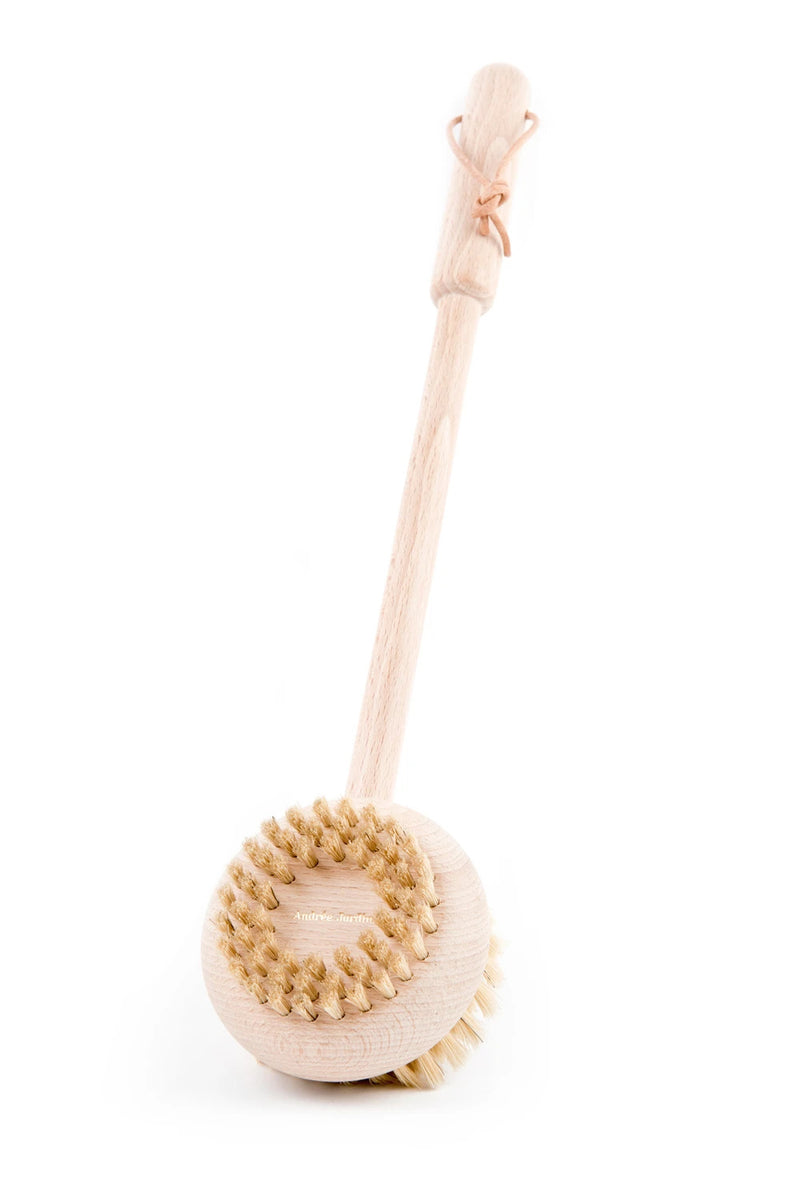 A Andrée Jardin Beechwood Handle Bath & Body Brush with natural bristles and a long handle, featuring a decorative wooden element shaped like a bow at the top, ideal as a sensitive skin brush, isolated on a white background.