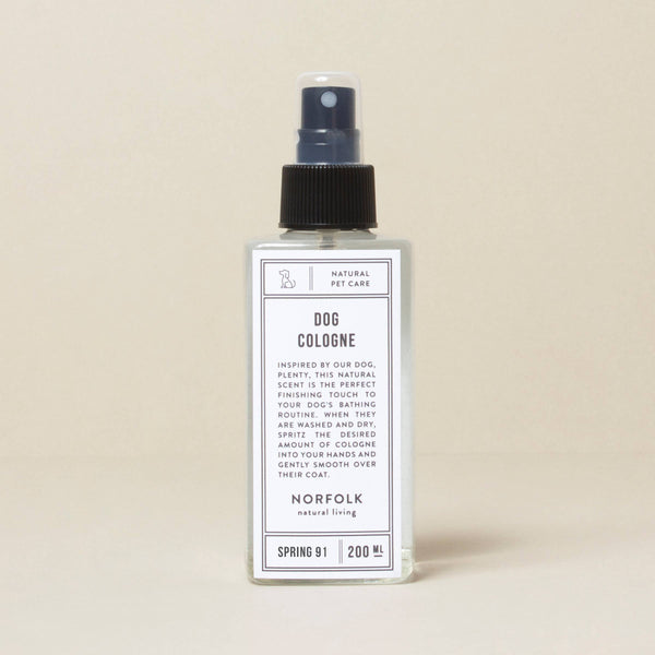 A transparent spray bottle labeled "Norfolk Natural Living Spring 91 Dog Cologne" with text for natural pet care in black print on a beige background. Details include spring 91 and 200 ml indicator, formulated with natural ingredients.
