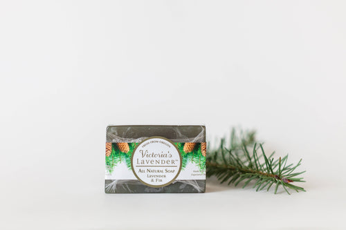 A bar of Victoria's Lavender Lavender & Fir Honey Glycerin Luxury Bar Soap with natural ingredients, featuring a lavender and fir scent, placed on a white background next to a small pine branch.