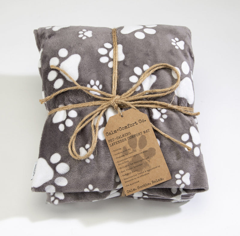 A folded gray Sonoma Lavender Pet Calming Mat - Large with white paw prints, tied with natural twine and featuring a brown paper tag infused with French lavender, on a white background.