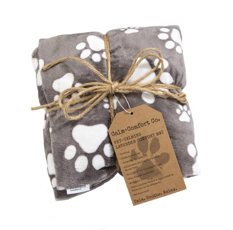 A soft, gray and white paw-print patterned Sonoma Lavender Pet Calming Mat - Medium tied with a natural twine and an attached brown Sonoma Lavender label, isolated on a white background.