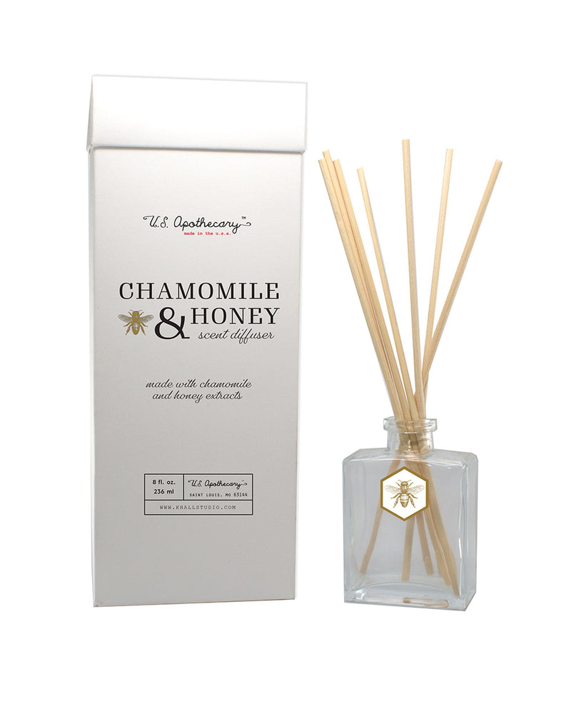 A U.S. Apothecary Chamomile & Honey Scent Diffuser Kit displayed with a rectangular box and a glass bottle. The bottle has several reed sticks inserted, featuring a decorative label.