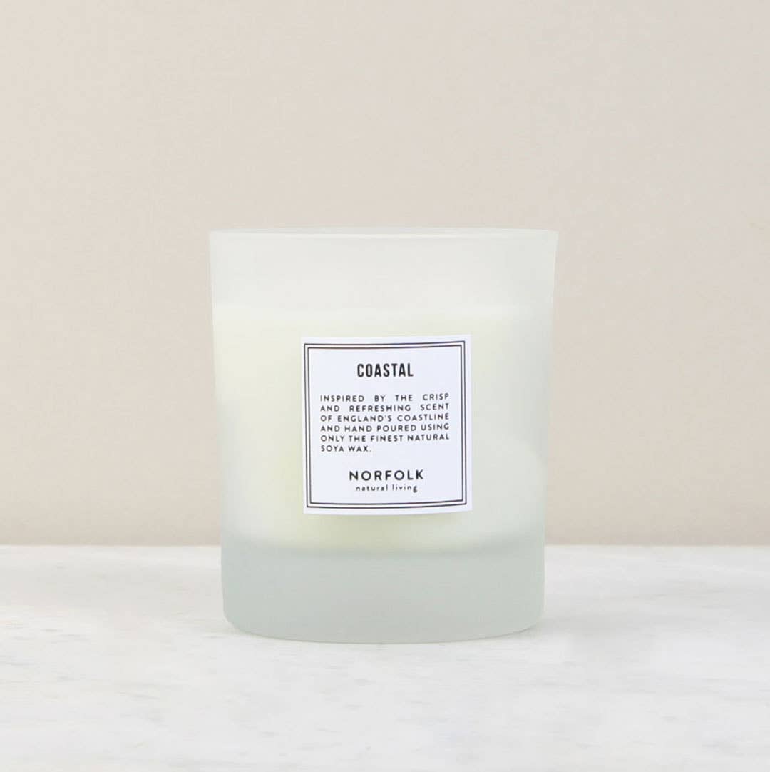 A Norfolk Natural Living Coastal Candle - 8oz labeled "coastal" with text describing its sea salt scent inspired by the north Norfolk coast, displayed against a neutral background.