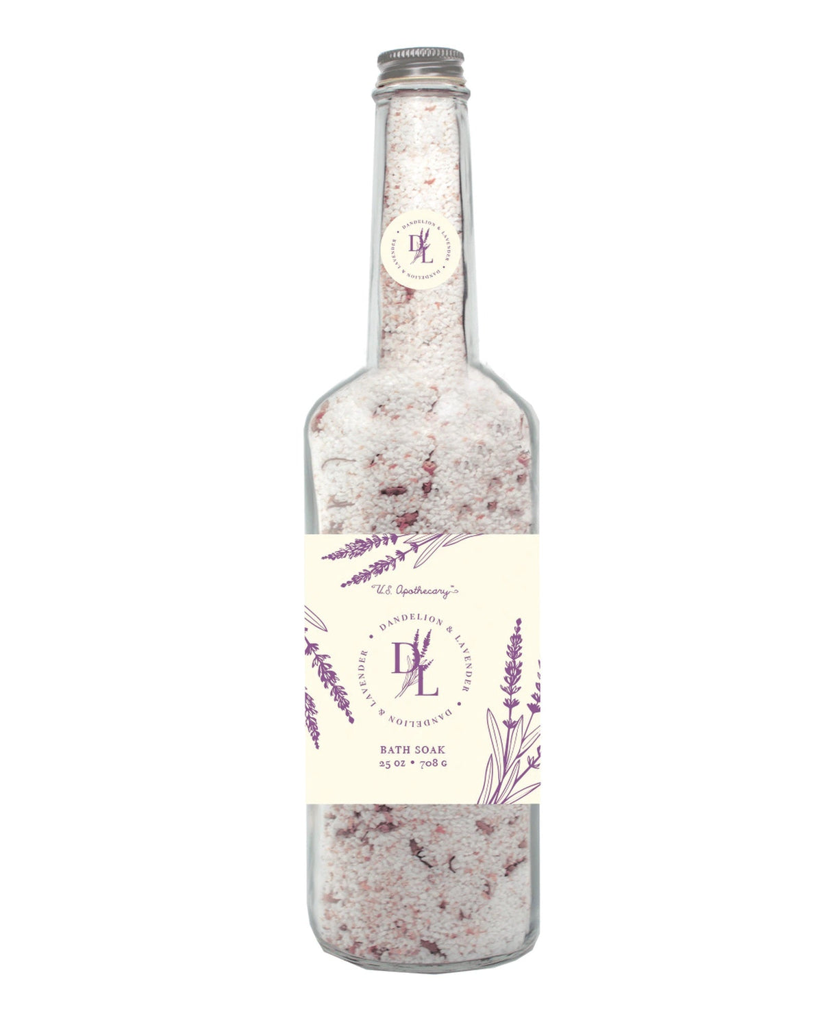 A clear, tall glass bottle containing U.S. Apothecary Dandelion & Lavender Bath Salt Soak, adorned with a cream label featuring lavender illustrations and elegant typography. The bottle cap has a small, round matching label.