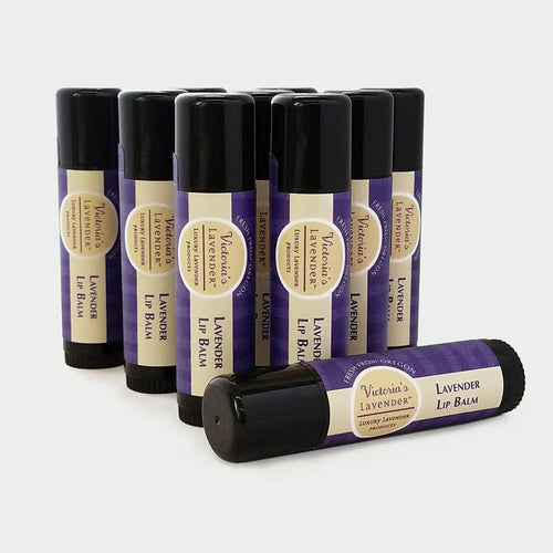 A collection of Victoria's Lavender Healing Lip Balm in black tubes with purple labels, arranged in a staggered formation on a white background.