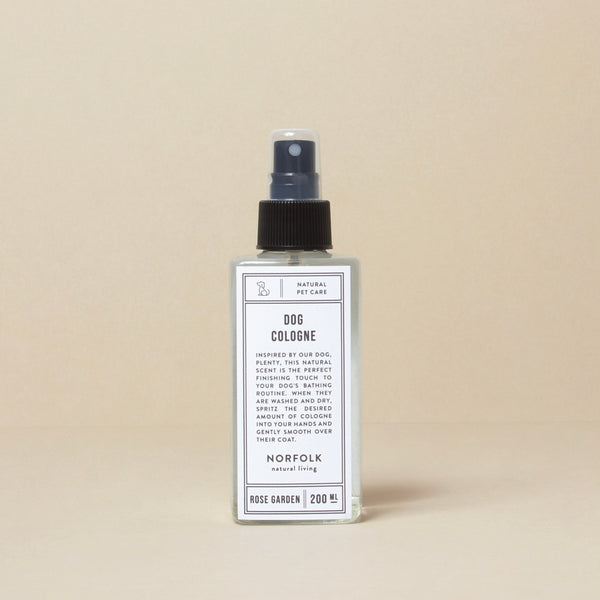 A bottle of Norfolk Natural Living Rose Garden Dog Cologne spray stands against a light beige background. The spray bottle, containing 200 ml of Norfolk Natural Living Rose Garden Dog Cologne, features a simple and elegant design.