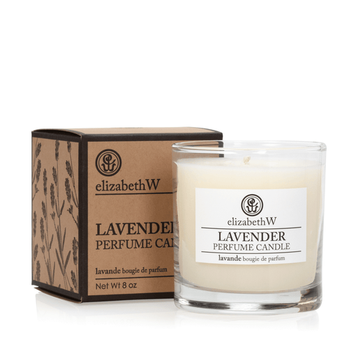 A scented elizabeth W Purely Essential Lavender Candle in a clear glass container beside its brown box with product details.