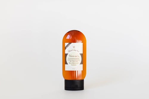 Orange Victoria's Lavender "Don't Bug Me" All Natural Bug Repellant Lotion bottle with a white label, featuring black and red text, stands against a plain white background. The label highlights its natural ingredients.