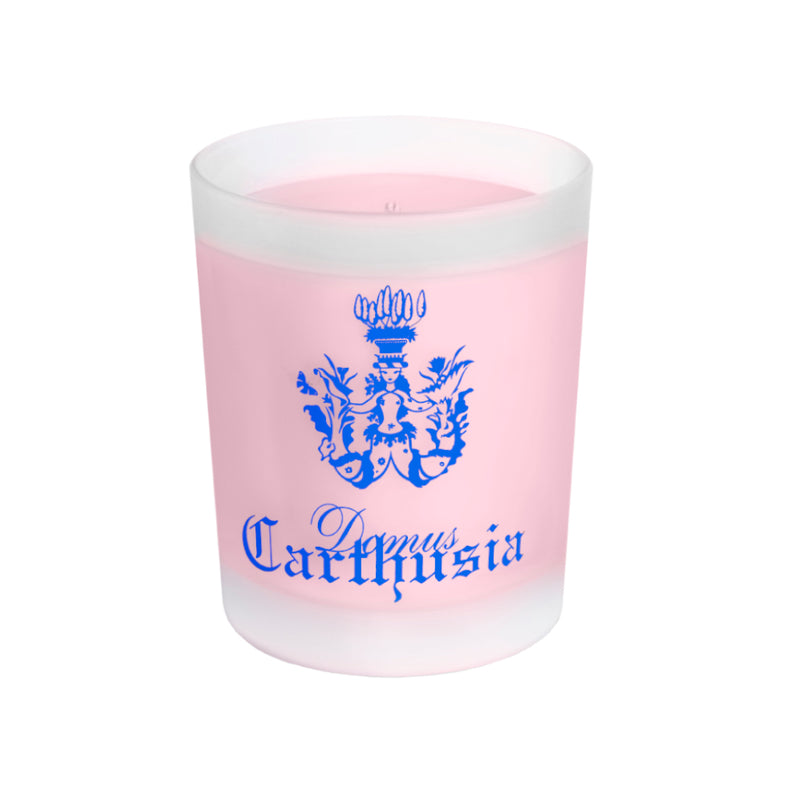 A perfumed pink Carthusia Fiori di Capri Candle in a Carthusia engraved glass holder with "Carthusia" written in blue gothic script and a blue intricate crest above the text. The wax inside the candle is.