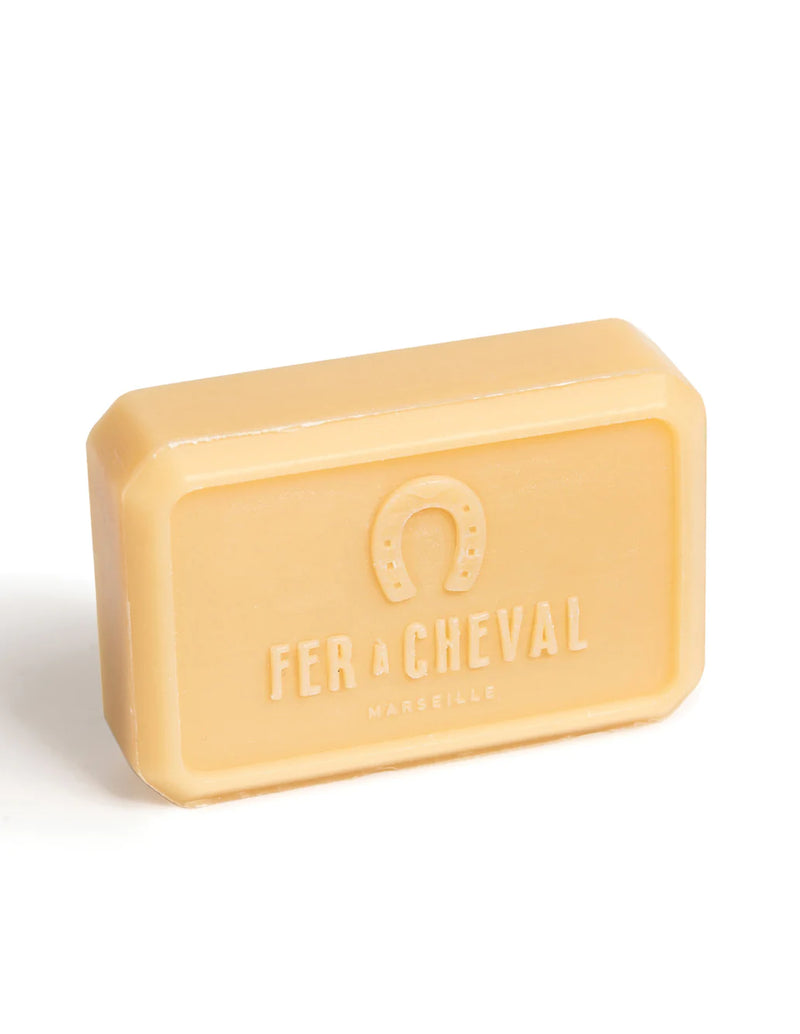A bar of Fer à Cheval Gentle Perfumed Soap Bar - Amber Jasmin 125g with shea butter in a solid beige color, isolated against a white background. The soap has the brand's logo embossed on it.