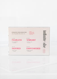 A Margot Elena Eau de Parfum Discovery Set box labeled "Infinite She Essence Exploration" on a reflective white surface, featuring words like "fearless," "vibrant," "inspired," and "empowered.